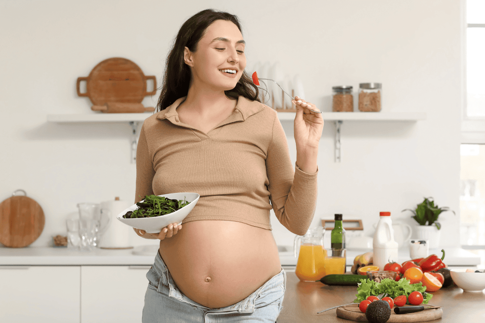 Pregnant woman enjoying a healthy salad in a bright kitchen setting