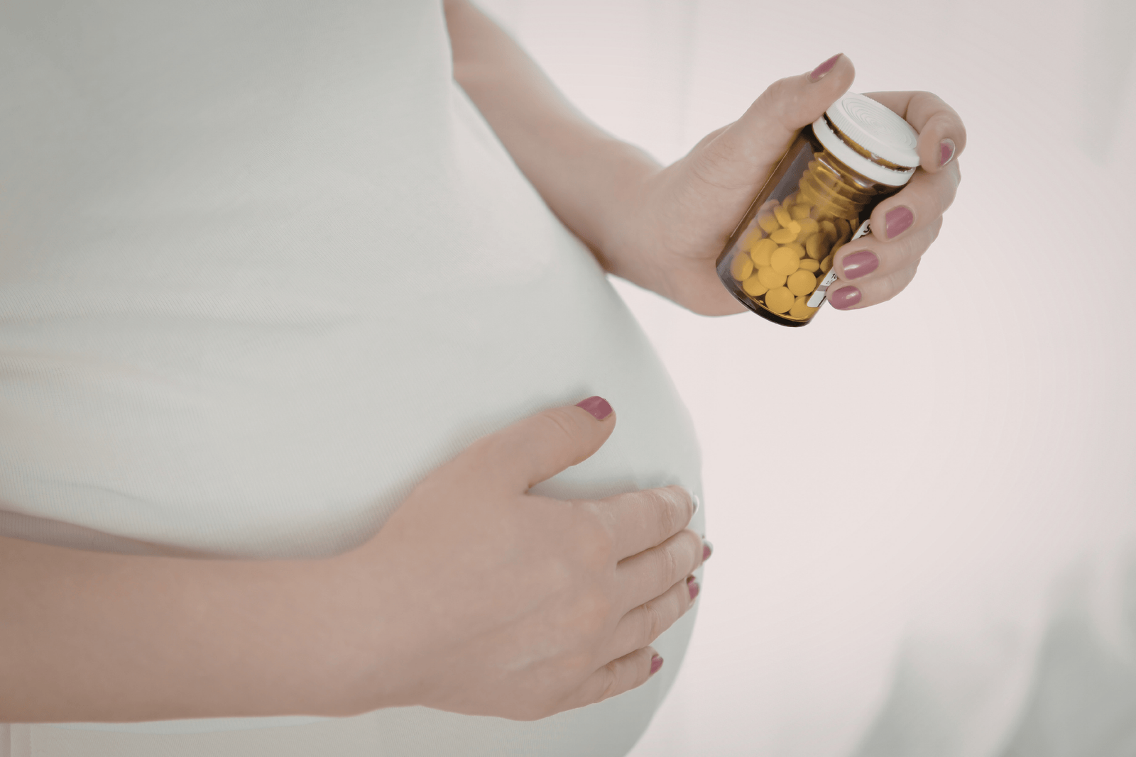 Pregnant woman holding a small pill bottle