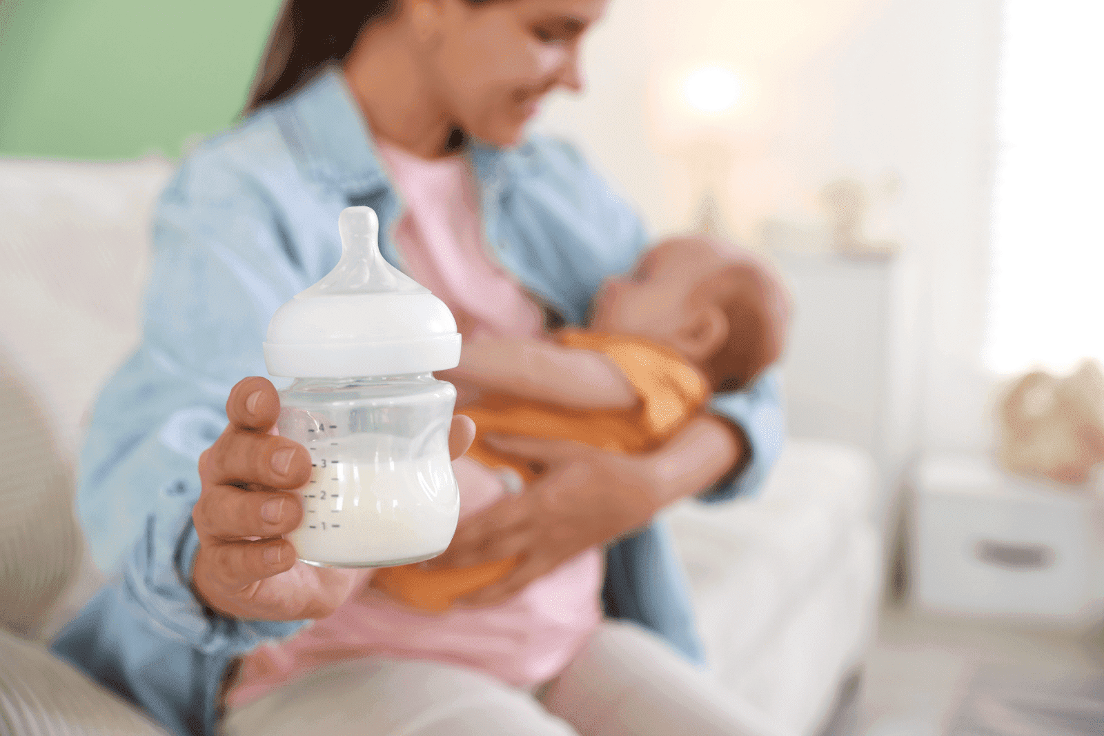Mother holding a bottle of breast milk while feeding her baby