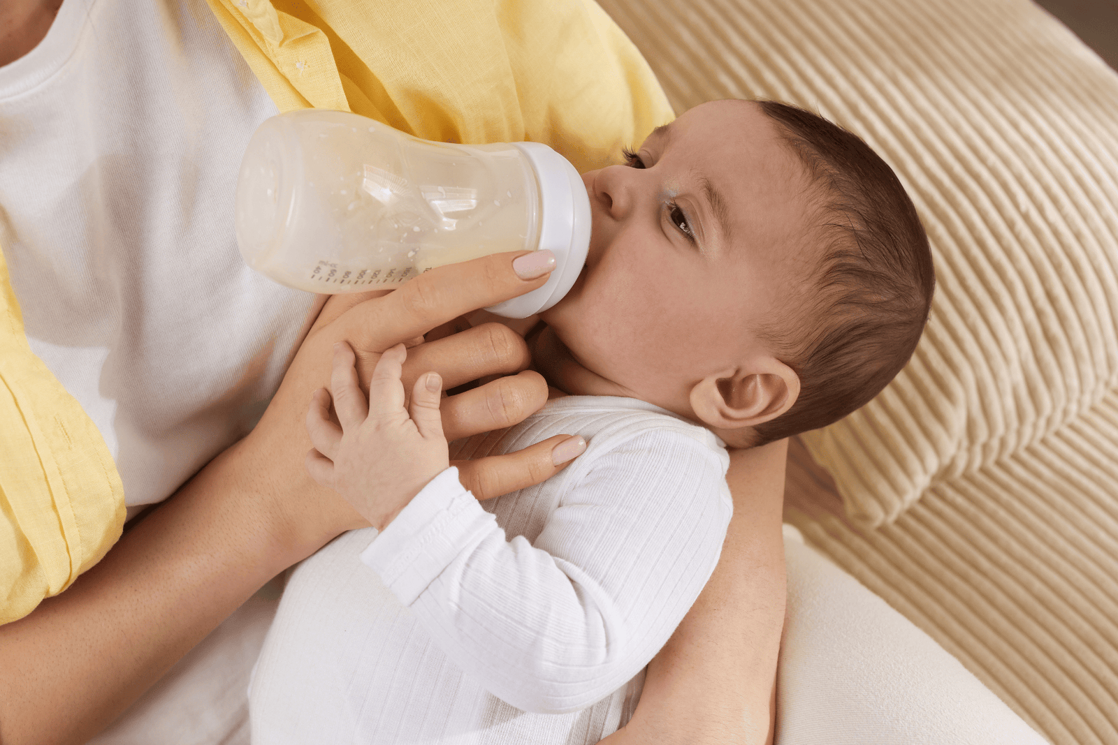 Adult feeding a baby with a bottle while holding them