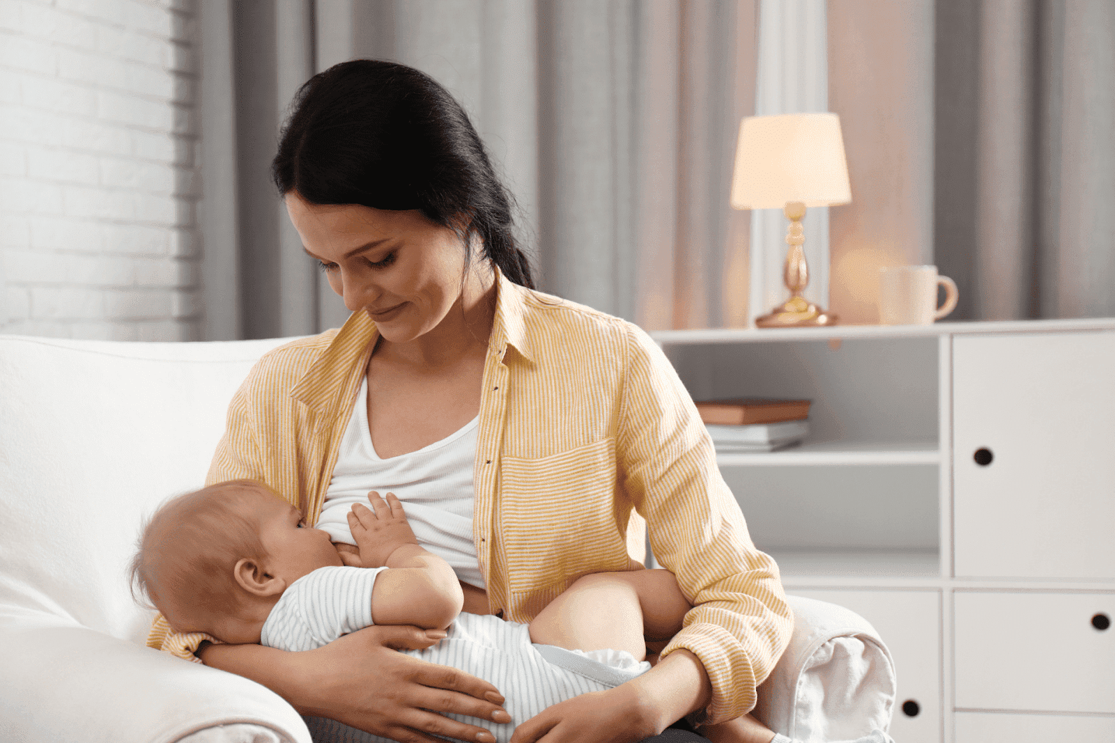 Mother breastfeeding her baby while sitting in a cozy living room