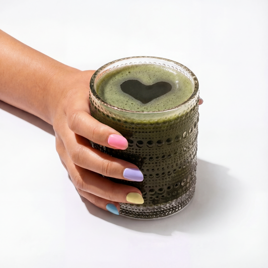 Daily Dose Greens smoothie with heart shape, held in hand.